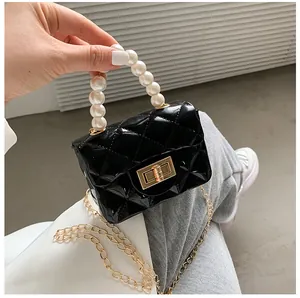 Detail of black quilted leather mini bag with white pearl handle and gold chain strap