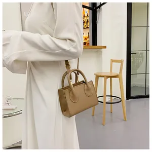 Detail of khaki square mini handbag with round top handles and adjustable strap