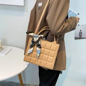 Khaki quilted crossbody bag with silk scarf handle detail, modeled with brown blazer