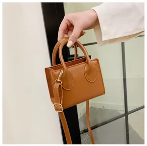Detail view of a tan mini crossbody bag with golden hardware and textured PU leather