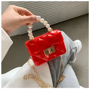 Macro detail of red quilted jelly bag featuring a mini pearl handle and gold twist lock