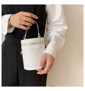 Nahaufnahme der weißen Zylindertasche mit Kroko-Prägung und goldenen Beschlägen