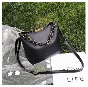 Detail of black bucket bag with gold metal bar, chain accent and gold FASHION lettering