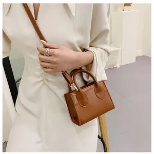 Detail view of the brown leather mini square bag featuring smooth texture and twin handles