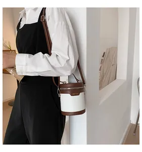 Detail einer zylindrischen Eimertasche mit braun-weißem Krokodilmuster an einem Model