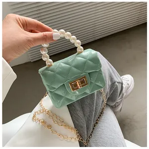 Detail of mint green quilted mini bag featuring pearl handle and golden chain strap