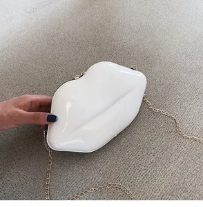 Detail view of white lip-shaped mini handbag with glossy finish and gold chain strap
