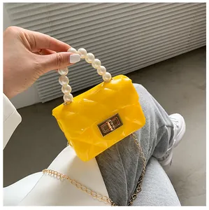 Detail of yellow jelly mini bag featuring pearl handle, quilted pattern and metal lock
