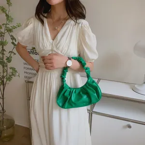 Detalle de bolso nube plisado verde claro con asa fruncida llevado por modelo