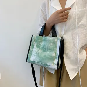 Detail view of small canvas tote bag featuring green tie-dye pattern and black straps