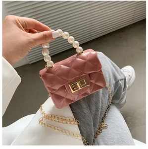 Detail of pink mini quilted bag with pearl handle and golden chain strap