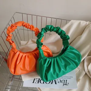 Detalle de bolsos plisados en naranja y verde vibrante dentro de un carrito de compras