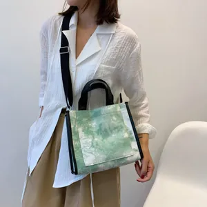 Detail of green tie-dye canvas tote bag with front pocket and adjustable strap