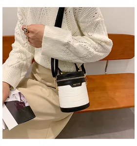 Detail einer Mini-Zylindertasche in Weißer Krokoprägung mit schwarzen Lederakzenten