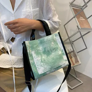 Detail of green and white tie-dye canvas tote bag with black leather handles and shoulder strap