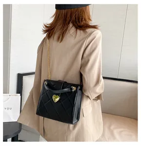 Vue arrière du mannequin portant un sac matelassé noir avec fermoir cœur doré et chaîne
