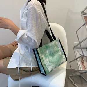 Detail of green and white tie-dye canvas tote bag with black straps and outer pocket