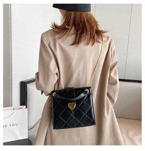Détail du sac matelassé noir avec fermoir coeur doré et bandoulière en chaîne