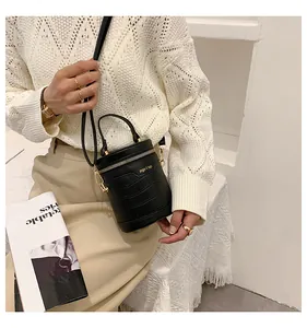 Detail der schwarzen Krokodil-Eimertasche mit goldener Hardware auf beigem Outfit