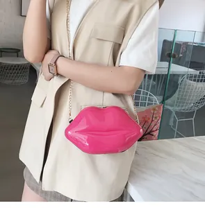 Detailed view of glossy rose red lip-shaped crossbody bag with gold chain strap on model