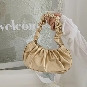 Detalle del asa fruncida en oro champán de la bolsa de hombro plisada para mujer