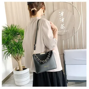 Detail of a black crossbody bucket bag with gold chain strap and fashion lettering