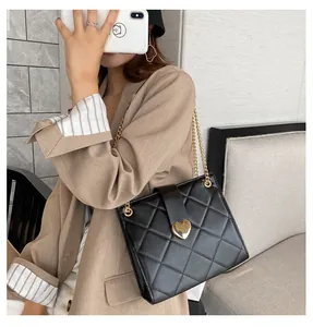 Détail d'un sac à bandoulière en cuir noir matelassé avec fermoir cœur en métal doré