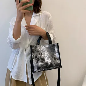 Lifestyle shot of large canvas tote bag with black ink pattern and adjustable shoulder strap
