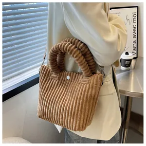 Detail of brown corduroy bucket bag texture with thick handle and metal strap hooks