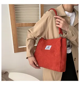 Detail of a bright orange corduroy tote bag showing the textured fabric and metal ring strap