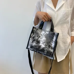 Artistic black and white landscape print canvas tote bag shown worn as a crossbody bag