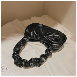 Detalle del bolso de hombro negro plisado en piel sintética suave con diseño elegante