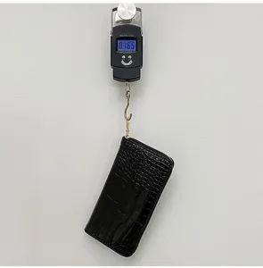 Báscula digital que muestra el peso de 0,165 kg de la cartera negra con piel de cocodrilo