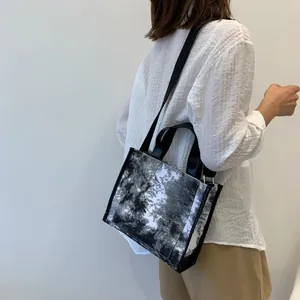 Detailed shot of an abstract black and white canvas bag worn by a model with a wide strap