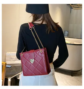 Détail du sac à main rouge matelassé avec boucle cœur dorée et bandoulière chaîne