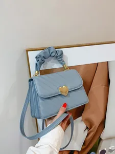 Detail of light blue quilted handbag with gold heart buckle and ruched handle