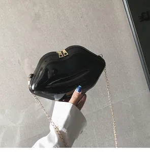 Close-up of black glossy lip-shaped mini chain bag with gold double zippers and texture