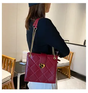 Détail du sac bandoulière matelassé bordeaux avec fermoir cœur doré et bandoulière chaîne