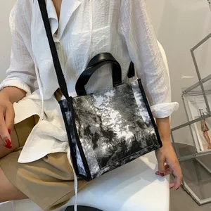 Detail shot of tie-dye canvas tote bag with black leather handles and long shoulder strap