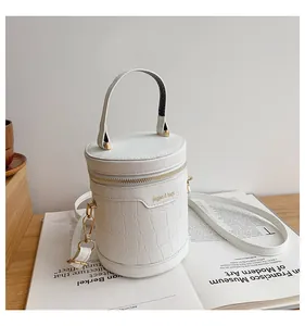 Details der weißen Zylindertasche mit Krokodilmuster und goldenen Metallbeschlägen