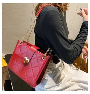 Détail du sac à bandoulière rouge matelassé avec fermoir cœur doré et chaîne