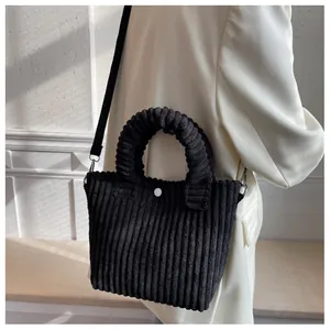 Detail of black corduroy bucket bag showing textured fabric and white round button closure