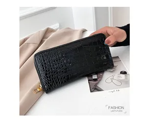 Primer plano de cartera larga negra con grabado de cocodrilo y cremallera dorada