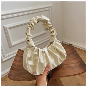 Detalle de cerca de la textura plisada de cuero sintético crema en el bolso nube