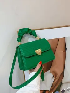 Detailed view of green quilted handbag featuring a gold heart-shaped metal twist lock
