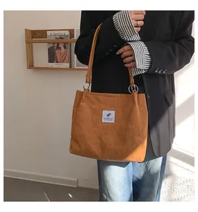 Detailed texture of brown corduroy tote bag featuring woven label and metal ring hardware