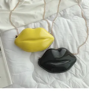 Detail of creative lip-shaped mini crossbody bags in yellow and black patent leather