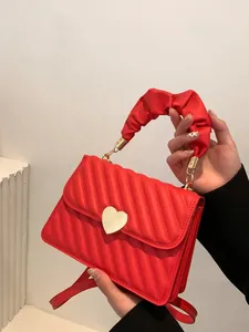 Detail of red quilted leather handbag with gold heart-shaped lock and ruched handle