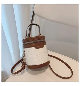 Detail der weißen Zylindertasche mit Krokoprägung, braunem Besatz und Goldbeschlägen