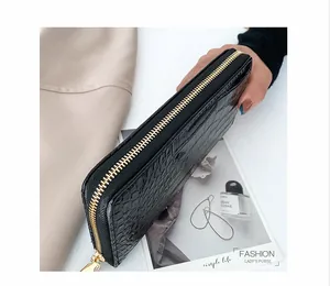 Vista detallada de cartera larga negra con textura de cocodrilo y cremallera dorada